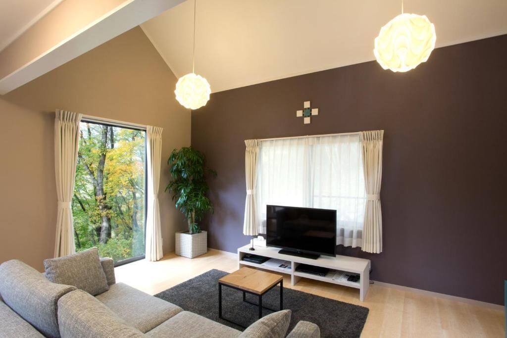 A modern living room with a sofa, television, and a potted plant.