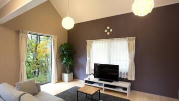A modern living room with a sofa, television, and a potted plant.