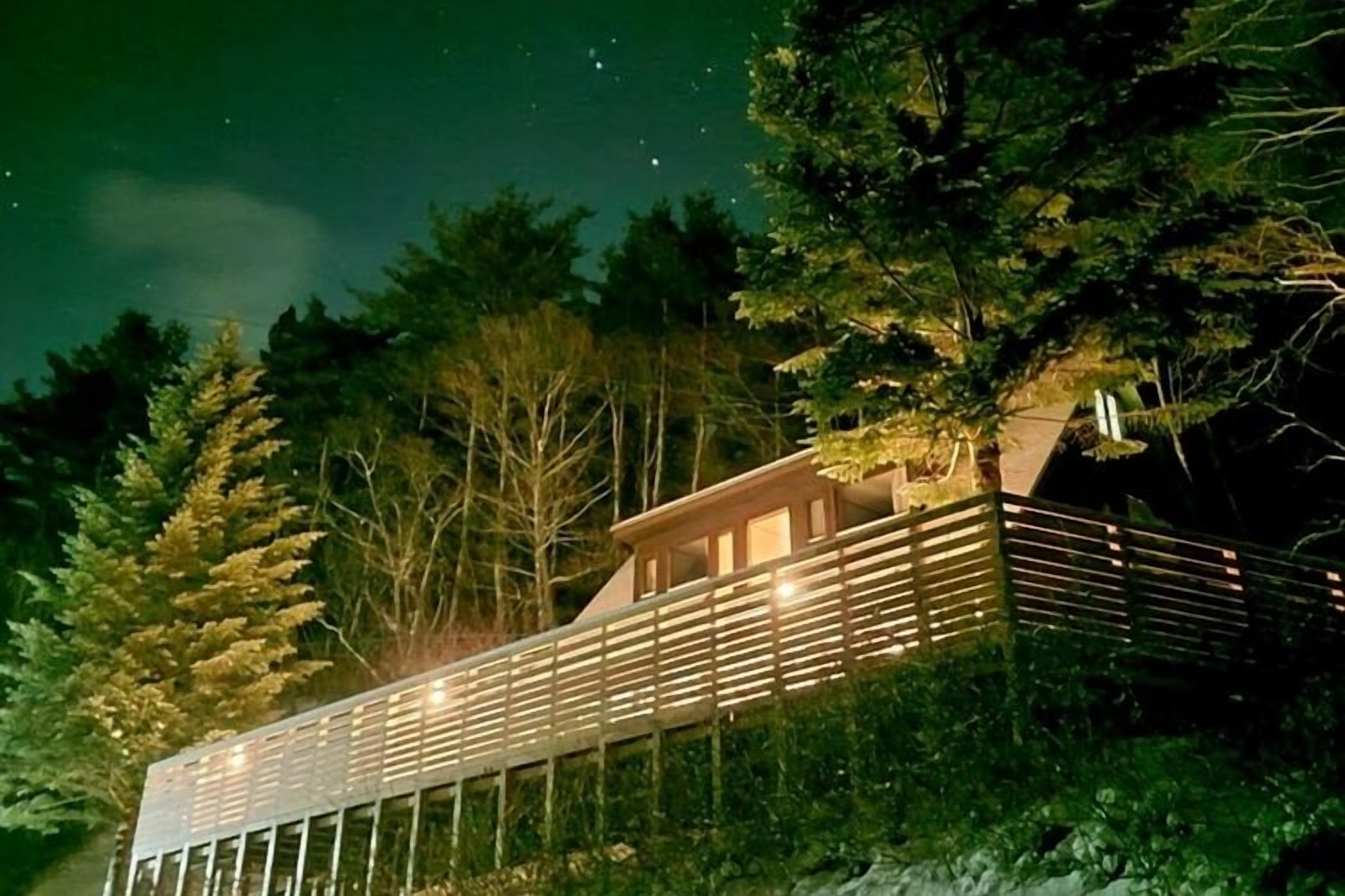 A modern building with a balcony, surrounded by trees.