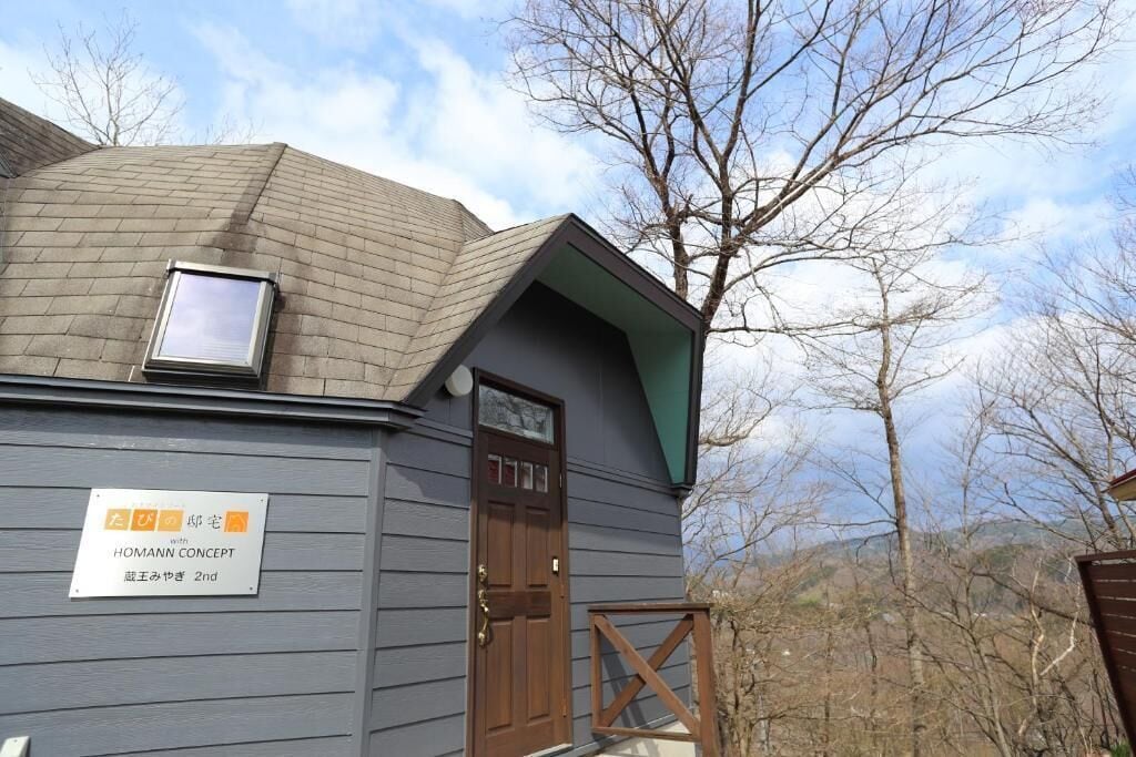 A small building with a sloped roof, a door, and a window. There is a sign on the door indicating 'HOMANN CONCEPT 2nd'.