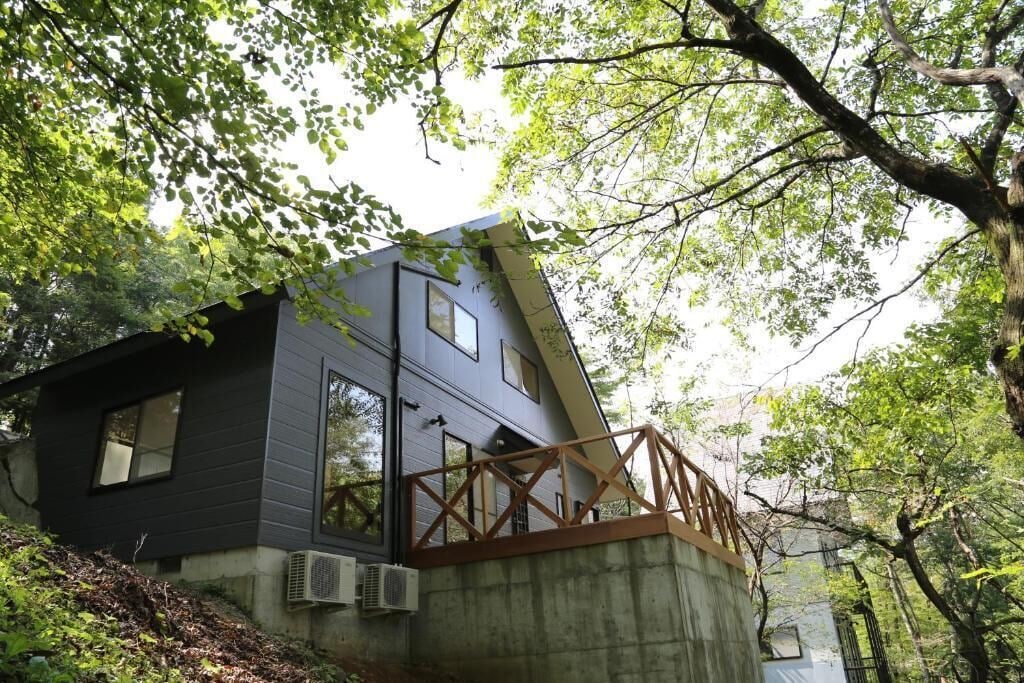 Una casa moderna con techo inclinado, amplias ventanas y base de hormigón.