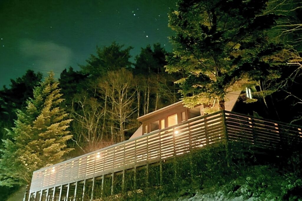 A modern building with a balcony, surrounded by trees.