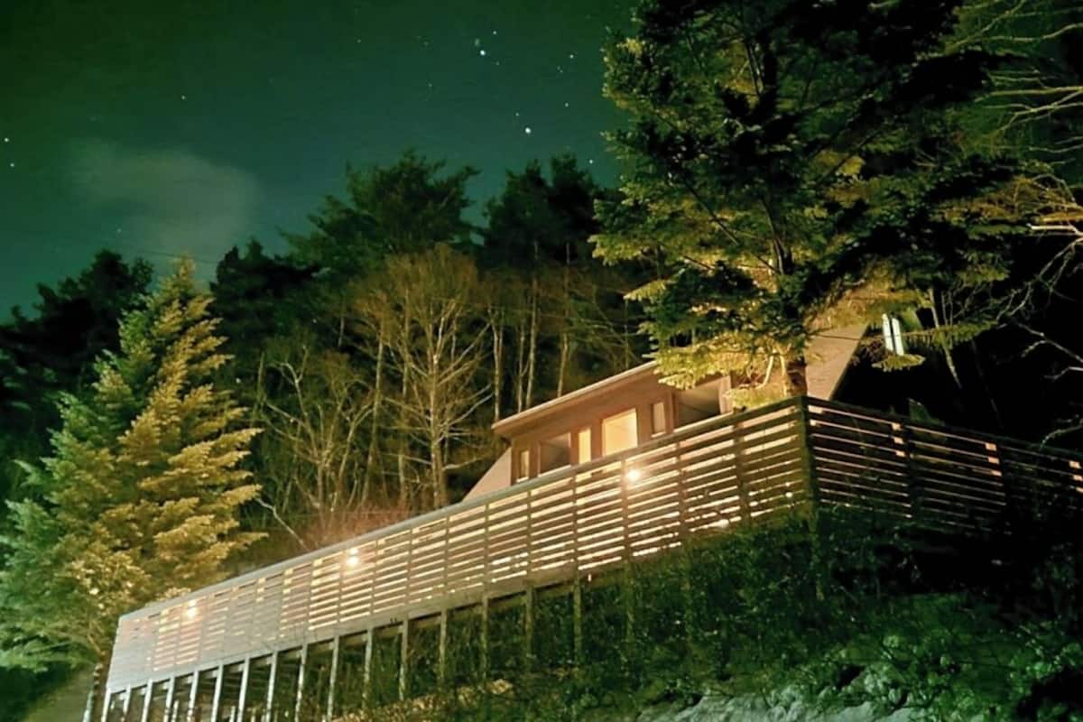 A modern building with a balcony, surrounded by trees.