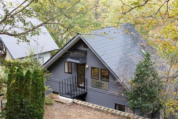 Une maison moderne avec un toit en pente, un petit porche et une enseigne indiquant « HOMANN CONCEPT ».