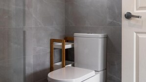 A modern bathroom with a toilet, a wooden chair, and a white door. - Luxury Granny Cottage Retreat in arms reach of Golf Course (Wilton)