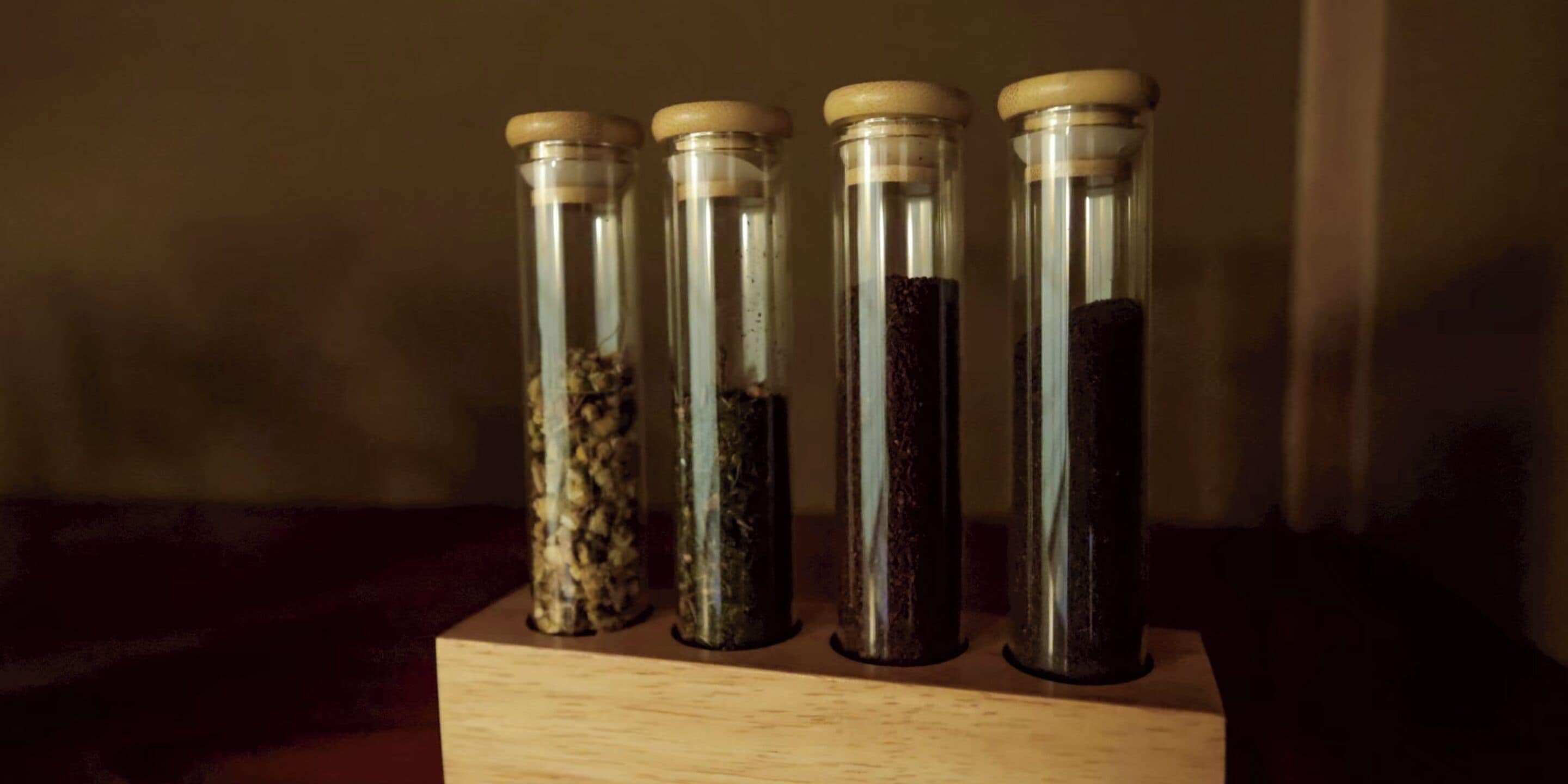 Four glass jars with wooden lids on a wooden block.