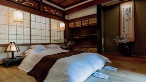 Un dormitorio de estilo japonés tradicional con una cama, lámparas de noche y una puerta corredera.