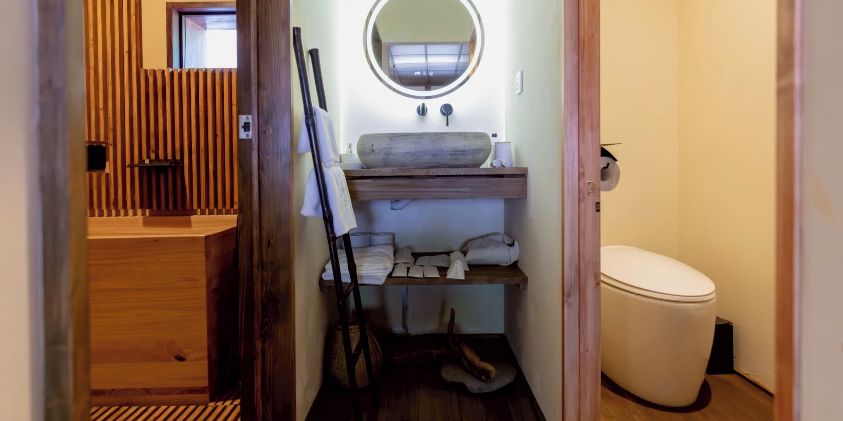 Un baño pequeño con tocador de madera, inodoro y un estante con toallas.