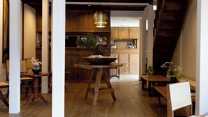 Un interior rústico con muebles de madera, una mesa central con un cuenco y una zona de cocina al fondo.