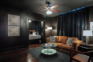 Ein modernes Wohnzimmer mit einer Ledersofa, einem Glastisch und einem Deckenventilator.