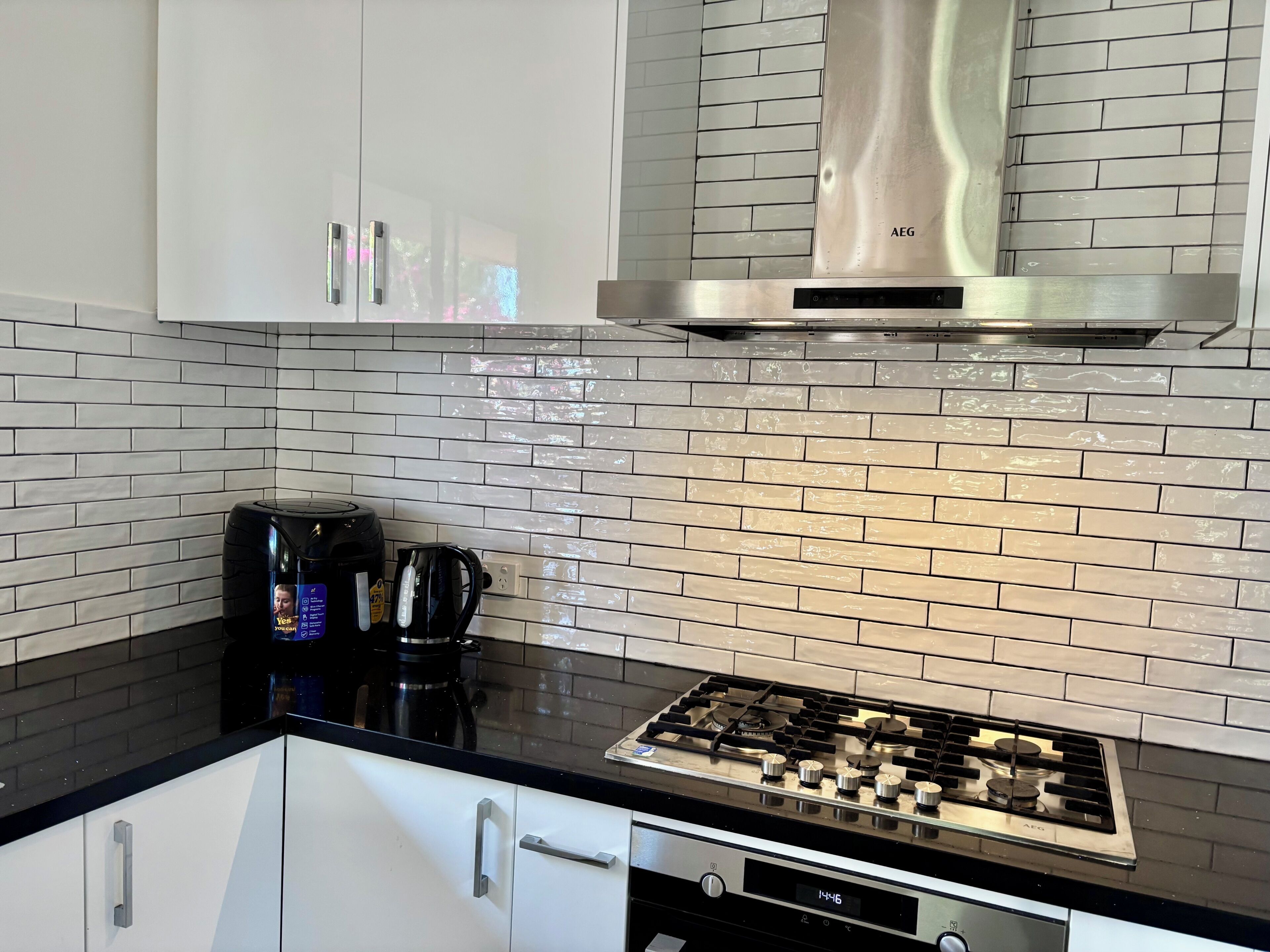 Una cocina con estufa a gas, cafetera y campana extractora de acero inoxidable.