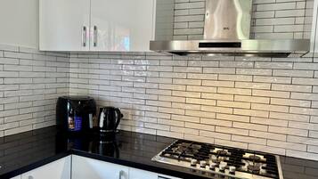 Una cocina con estufa a gas, cafetera y campana extractora de acero inoxidable.
