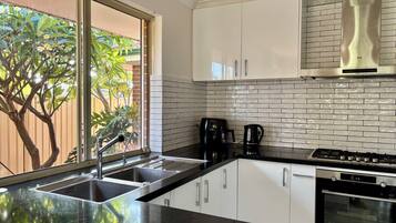 A modern kitchen with a large window, stainless steel appliances, and white cabinetry.