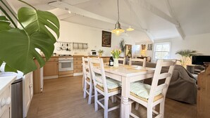 Une cuisine spacieuse avec des meubles en bois, un coin repas avec une table et des chaises en bois, et un salon confortable avec un canapé.
