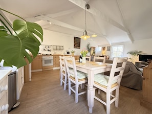 Una cocina amplia con armarios de madera, un comedor con mesa y sillas de madera, y un espacio de sala de estar acogedor con un sofá.