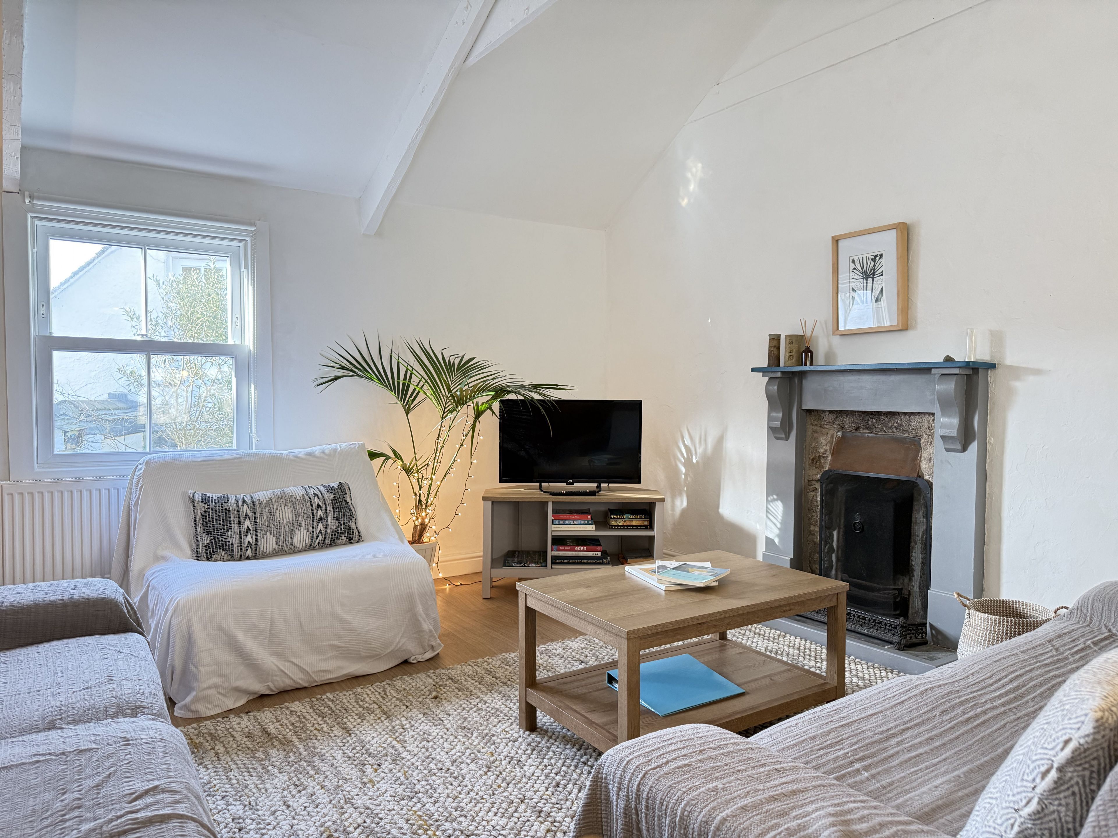 A living room with a fireplace, a television, a sofa, a coffee table, and a large window.