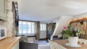 A cozy kitchen with a stone wall, a wooden dining table, and a gray sofa. - Coasters House a spacious St Ives townhouse in the hidden quarter (St Ives)