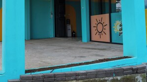 A building entrance with a blue and yellow color scheme, a water dispenser, and a door leading inside. - INSTAY Hotel Dieng Chill Serenity (Garung)
