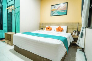 Habitación de hotel con cama, mesita de noche de madera, un cuadro colgado en la pared y ventana con cortinas.