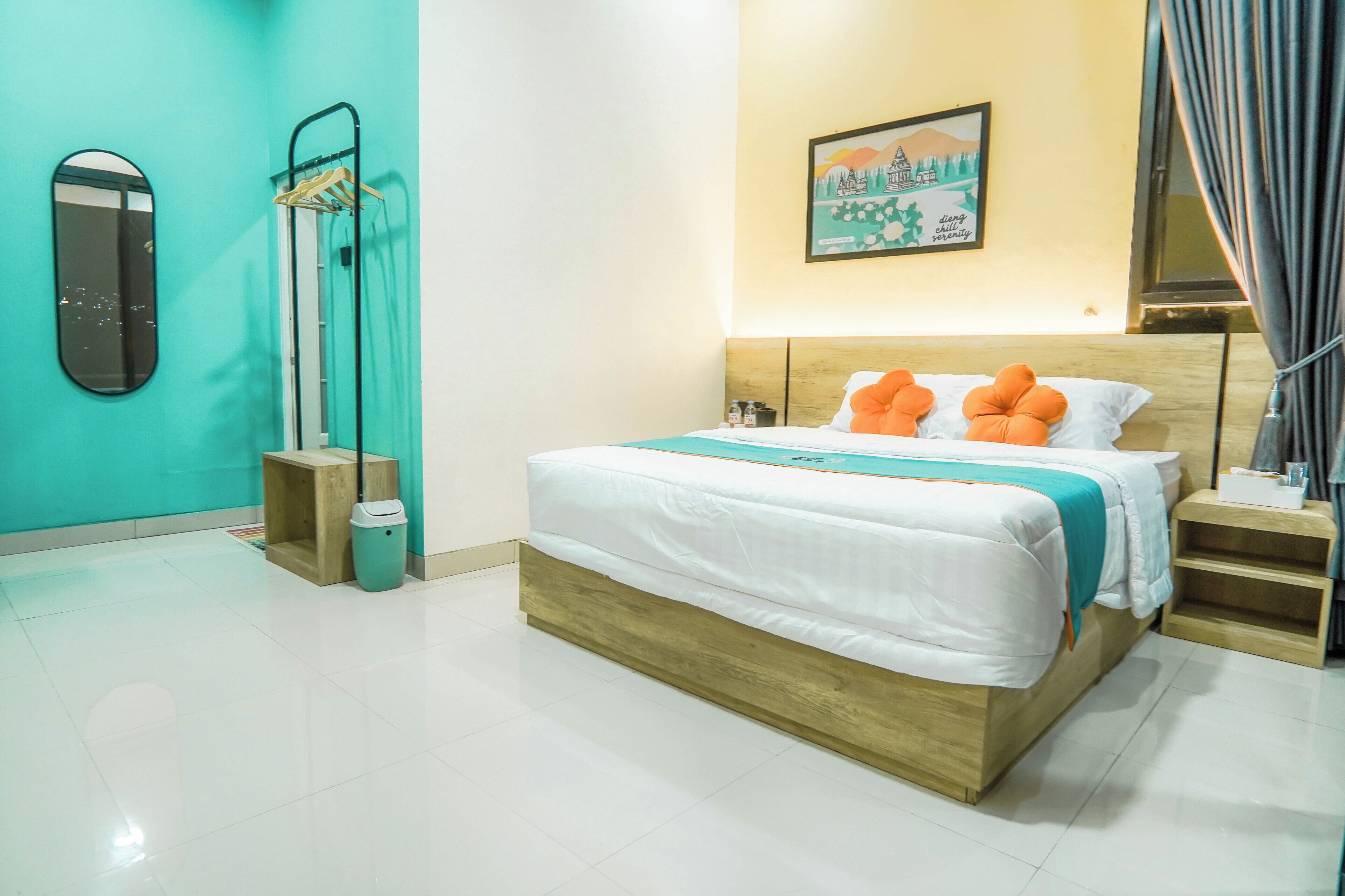 Une chambre d’hôtel avec un lit, un miroir, un tableau au mur et une fenêtre avec des rideaux.