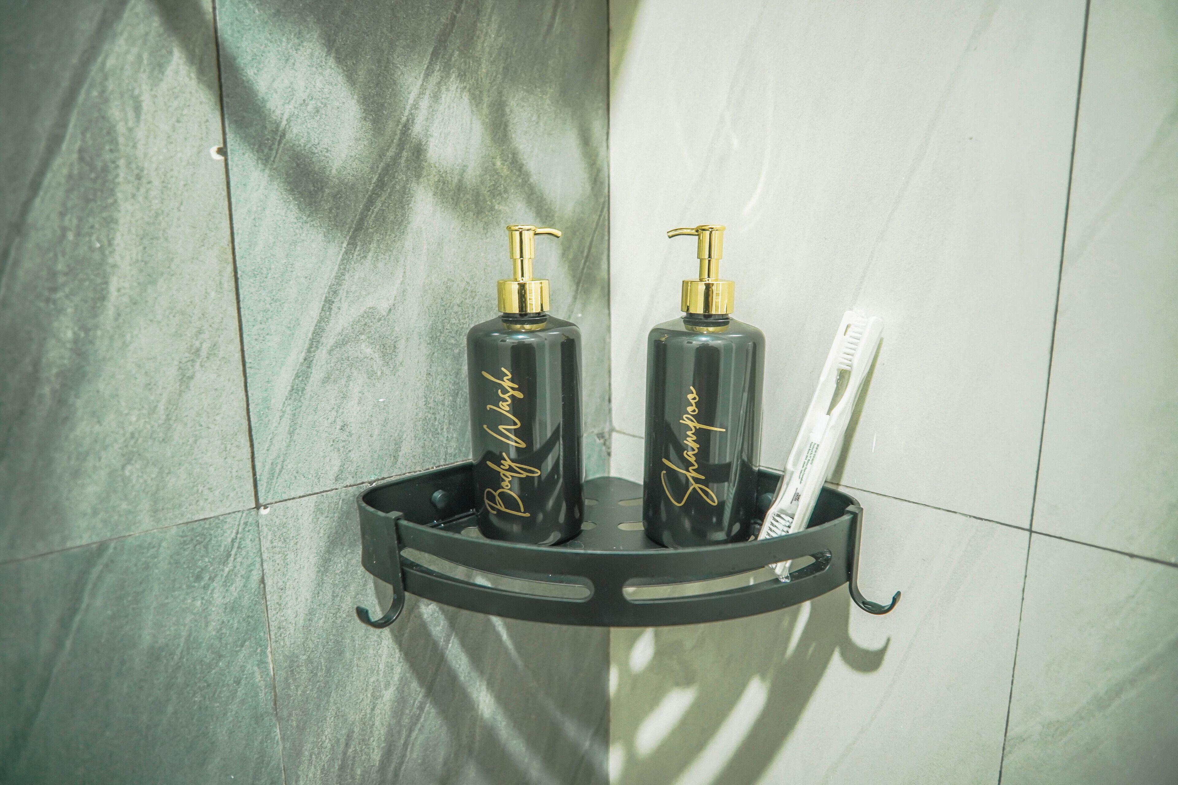 Une salle de bain avec un distributeur de savon noir et un porte-brosse à dents fixé sur un étagère murale.