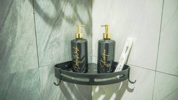 Une salle de bain avec un distributeur de savon noir et un porte-brosse à dents fixé sur un étagère murale.