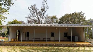 A covered outdoor pavilion with a tiled roof, benches, and a small table. - Camp Sethumadai (Sethumadai)