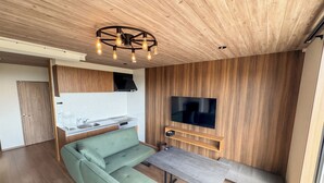 Un espacio habitable moderno con sofá, mesa de comedor, televisor y paneles de pared de madera.