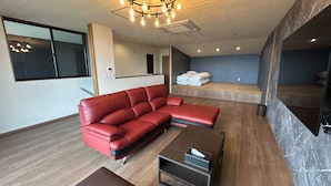 Una sala de estar moderna con un sofá seccional rojo, una mesa de centro de madera y una mesita auxiliar.
