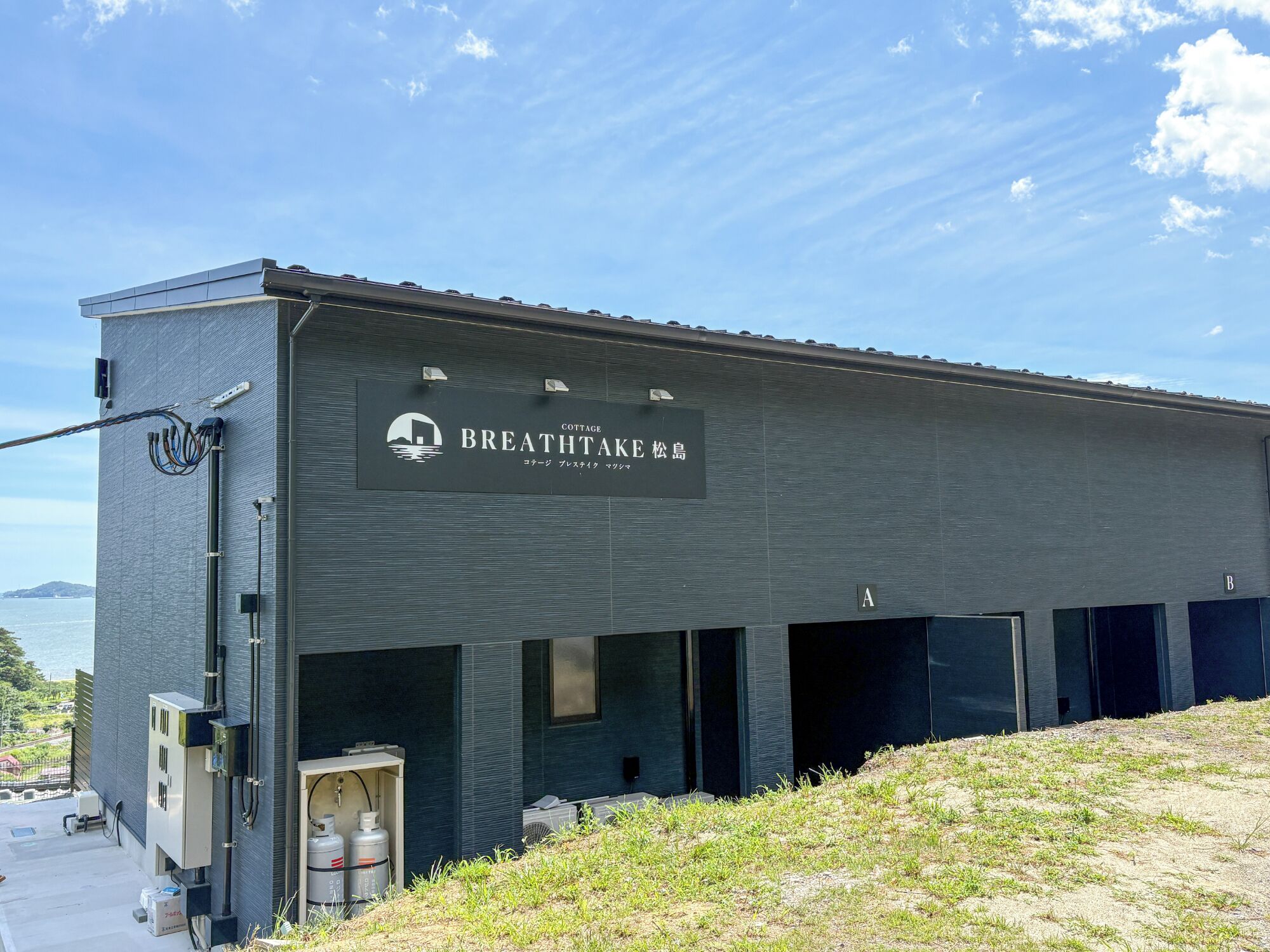En byggnad med en skylt som lyder ”BREATHTAKE COTTAGE” och en utsikt över havet i bakgrunden.