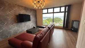 Una sala de estar moderna con un ventanal grande, un televisor de pantalla plana, un sofá y una mesa de centro.