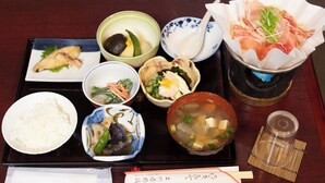 En bakke med forskellige japanske retter, herunder ris, suppe og sashimi.