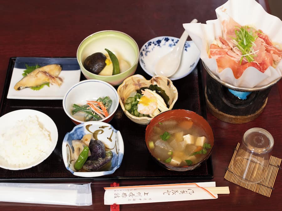 A variety of Japanese dishes on a tray, including rice, soup, and sashimi.