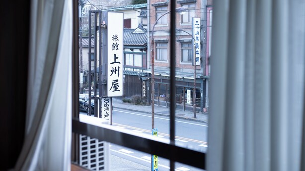 Udsigt gennem et vindue, hvor en bygning med påskriften 'Nihonbashi' og 'Hotel' på japansk er synlig.