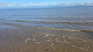 En strand med vågor, en sandstrand och en avlägsen horisont.