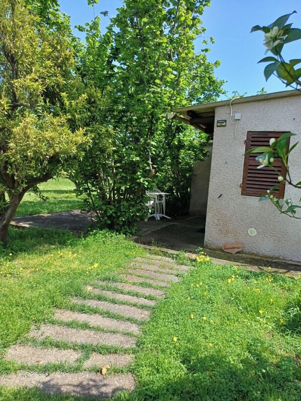 A pathway leading to a building with a small garden area, a bench, and a sign with a heart-shaped cutout.