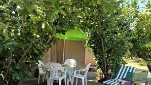 Ein Terrassenbereich mit Liegestühlen, einem Tisch und einer überdachten Sitzgelegenheit.