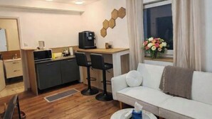Una sala de estar moderna con un sofá, una mesa de centro y una zona de cocina con cafetera.
