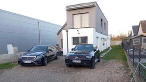 Dos coches estacionados frente a un edificio moderno con camino de grava.