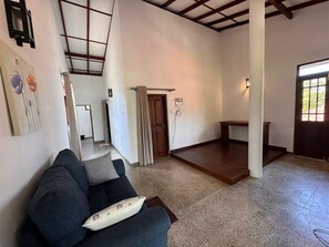 A living room with a sofa, a wooden table, a door, and a staircase leading to another room.