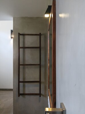 A room with a wooden ladder leaning against a wall, a metal-framed mirror, and a light fixture on the wall. - Sereniqe Heaven: Experience the Difference of True Serenity (Hikkaduwa)