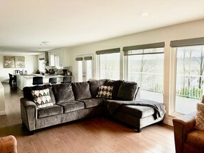 A modern living room with a sectional sofa, a dining area, and a kitchen in the background. - 4 Bed 2Bath entire unit. Sleep 12. Same level. Nice view (Coquitlam)