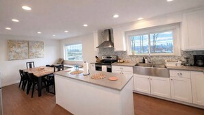 A modern kitchen with white cabinetry, a central island, and a large window offering a city view.