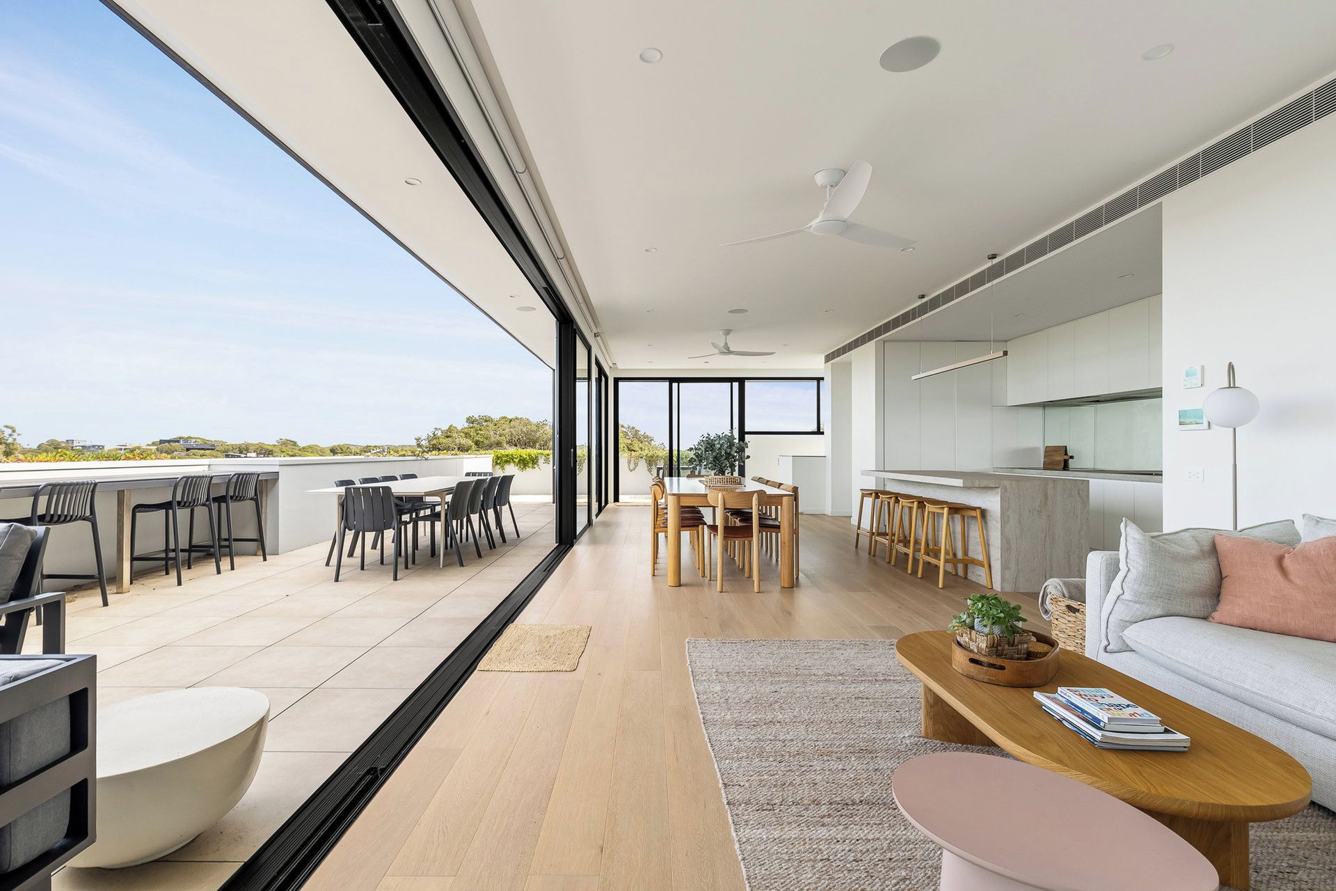 A modern interior with a dining area, kitchen, and seating space with a view.