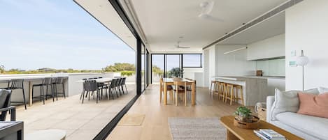 A modern interior with a dining area, kitchen, and seating space with a view.