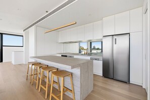 Eine moderne Küche mit einer zentralen Kochinsel, Edelstahlgeräten und Holzbarhocker.