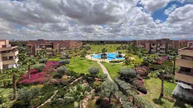 A residential area with apartment buildings, a swimming pool, and well-maintained gardens. - Apartment Prestigia Jade pool and garden view (Marrakech)