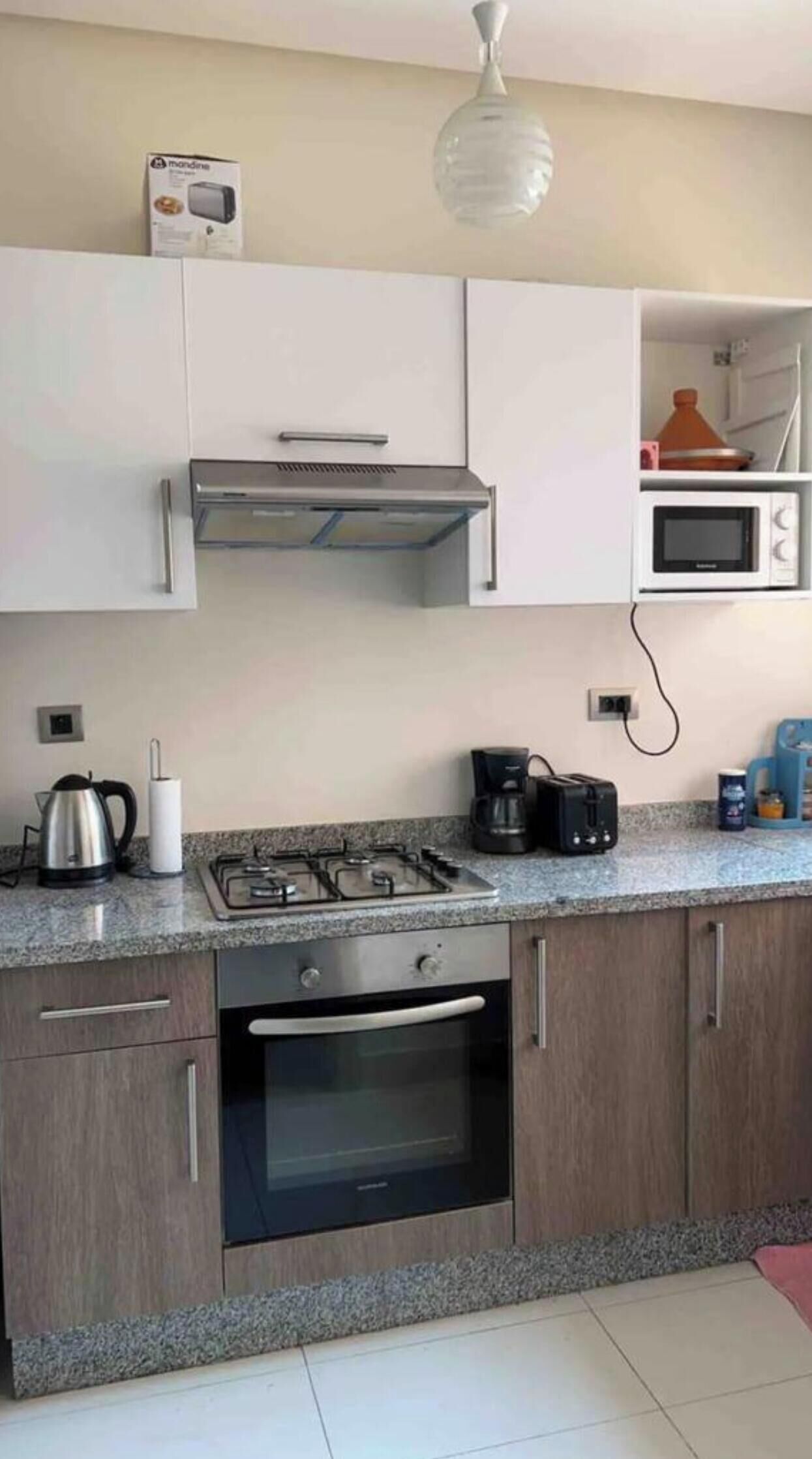A modern kitchen with a gas stove, oven, microwave, and a hanging light fixture.