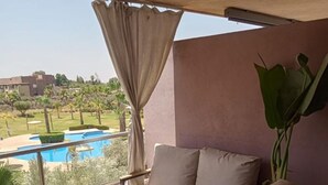 A balcony with a sofa, a small table, and a potted plant. - Apartment Prestigia Jade pool and garden view (Marrakech)