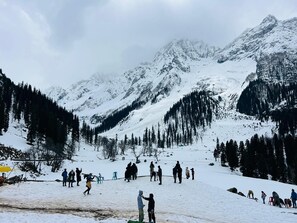 A snowy mountain landscape with people skiing and walking. - Hotel Ilhan Sonamarg (Sonamarg)